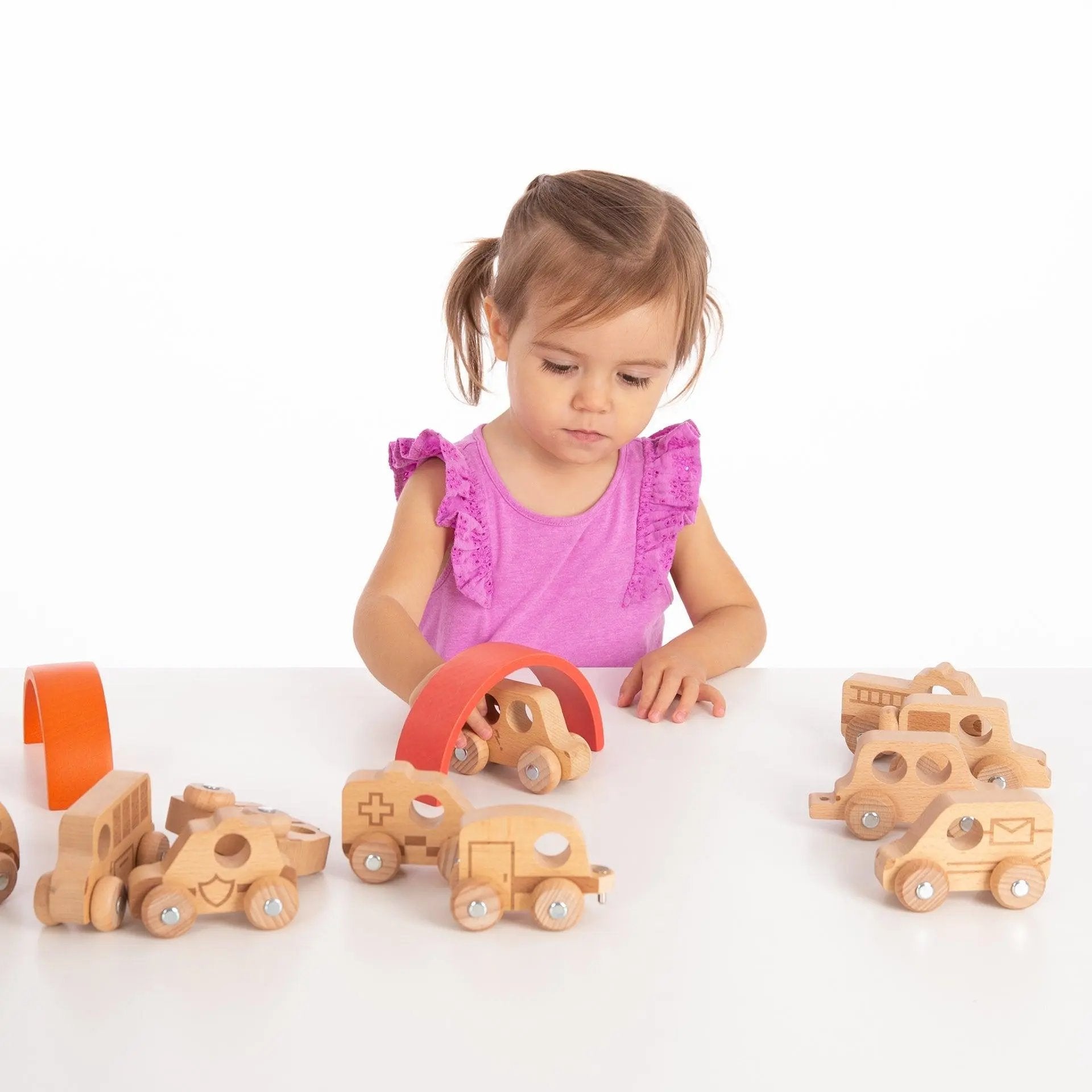 Child playing with wooden toy cars on a white background