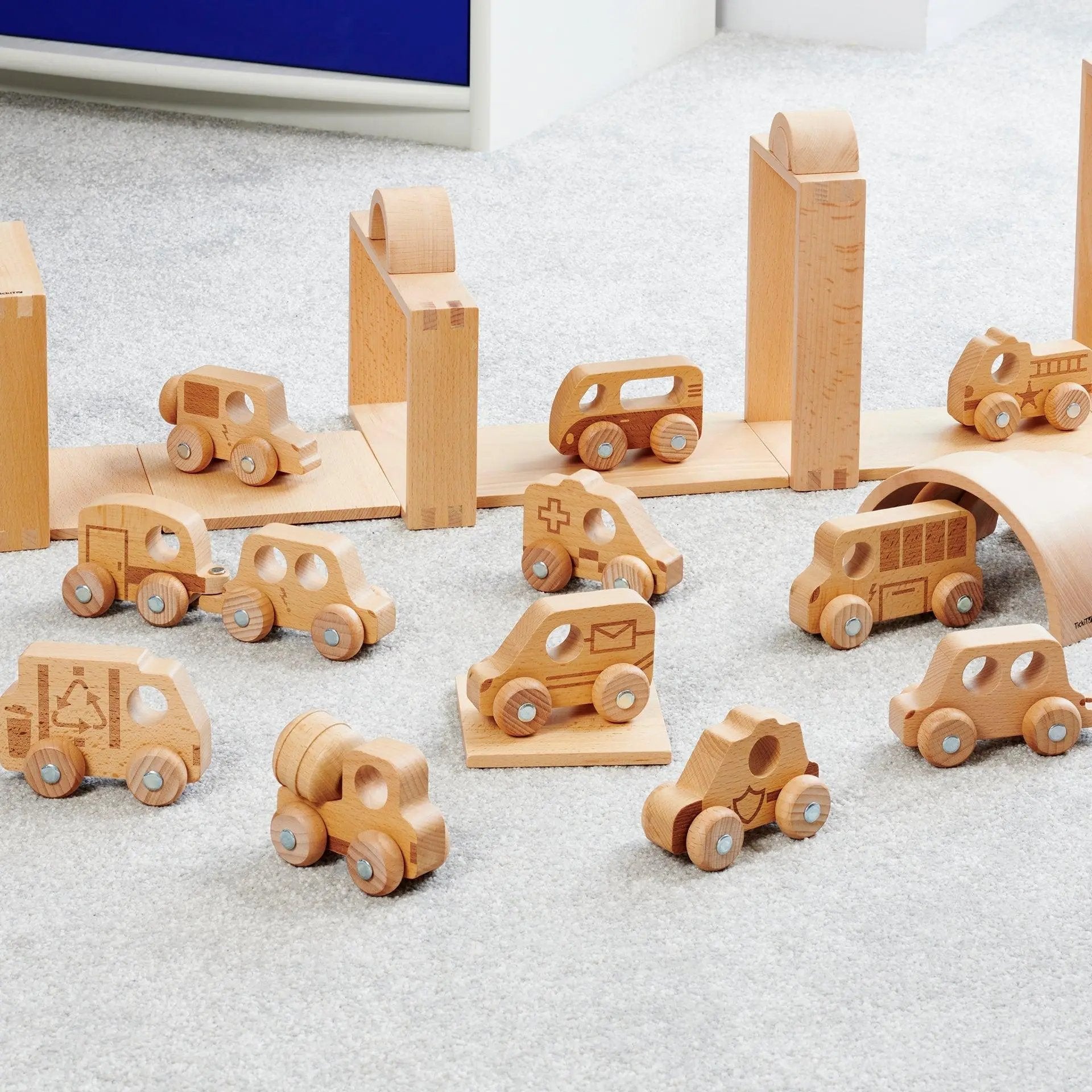 Set of wooden toy cars and buildings on a grey surface