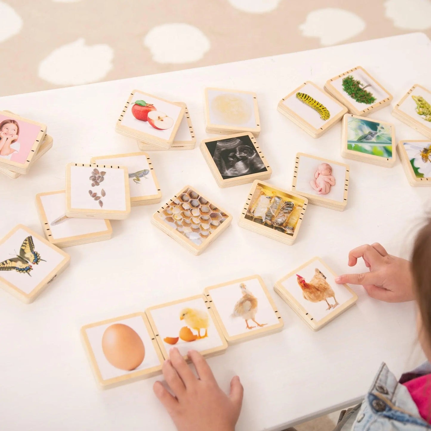 Children playing with educational wooden cards on a white surface