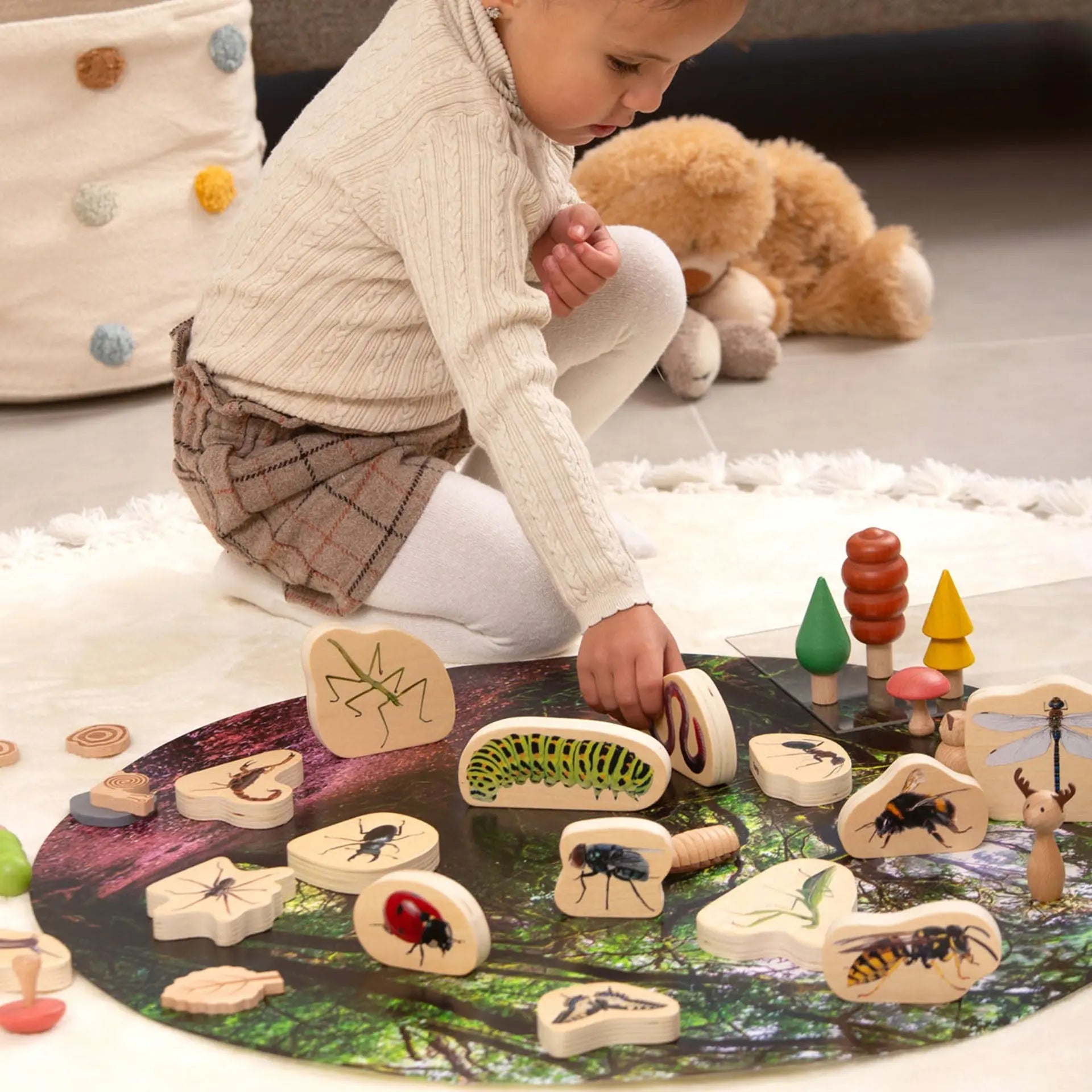 Child playing with wooden nature-themed toys on a soft surface