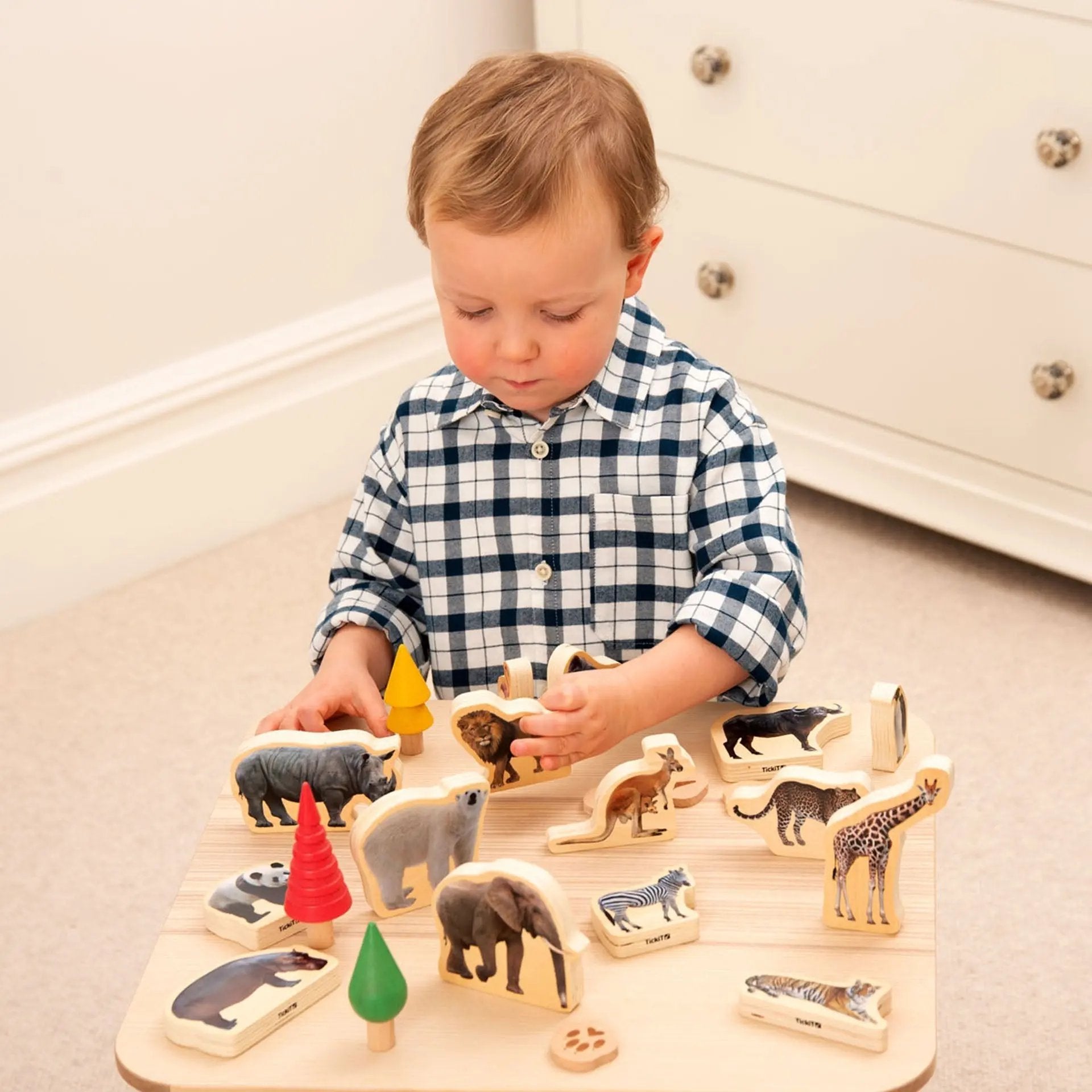 Child playing with wooden animal blocks on a light-coloured floor.