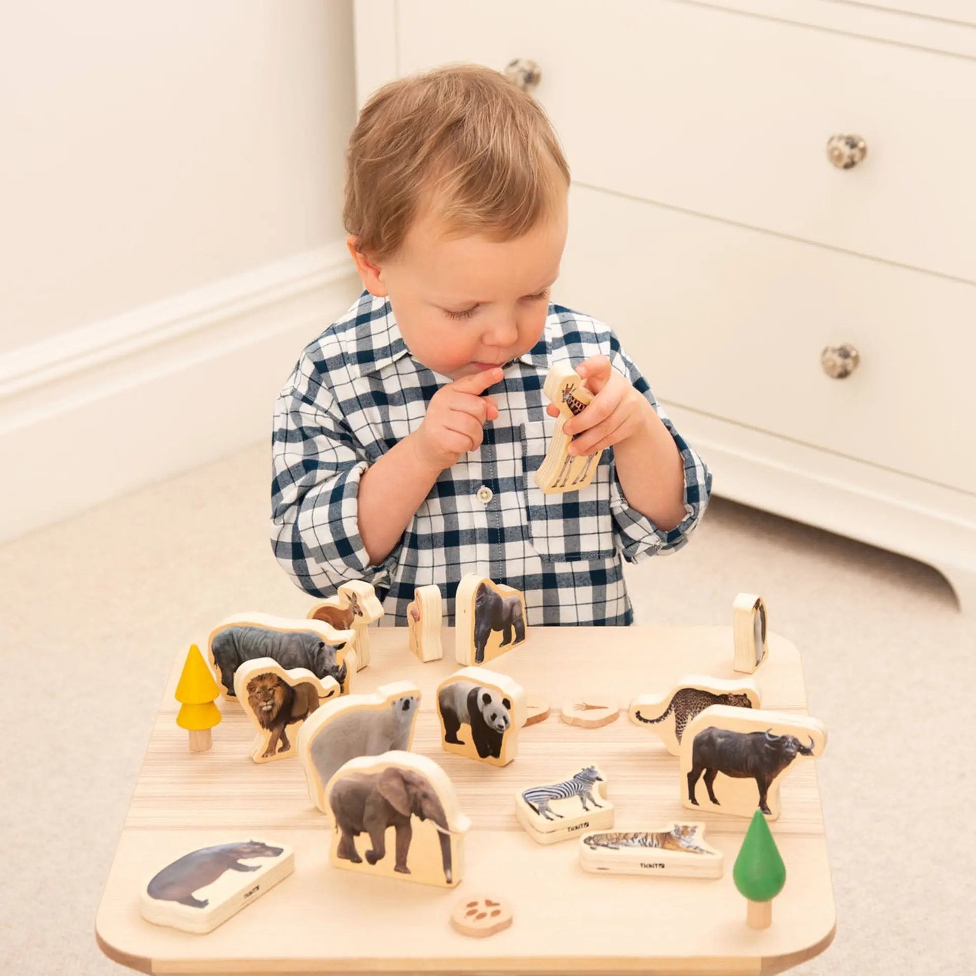 Child playing with wooden animal figures on a tray