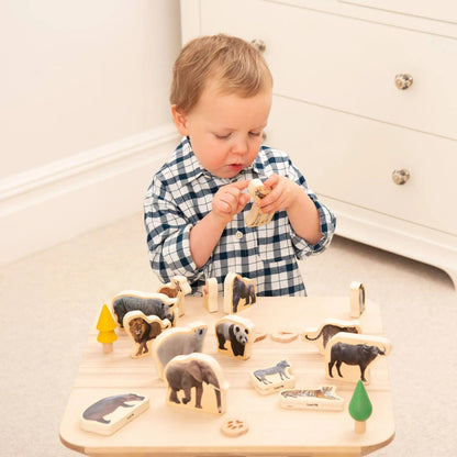 Child playing with a wooden animal puzzle on a table.