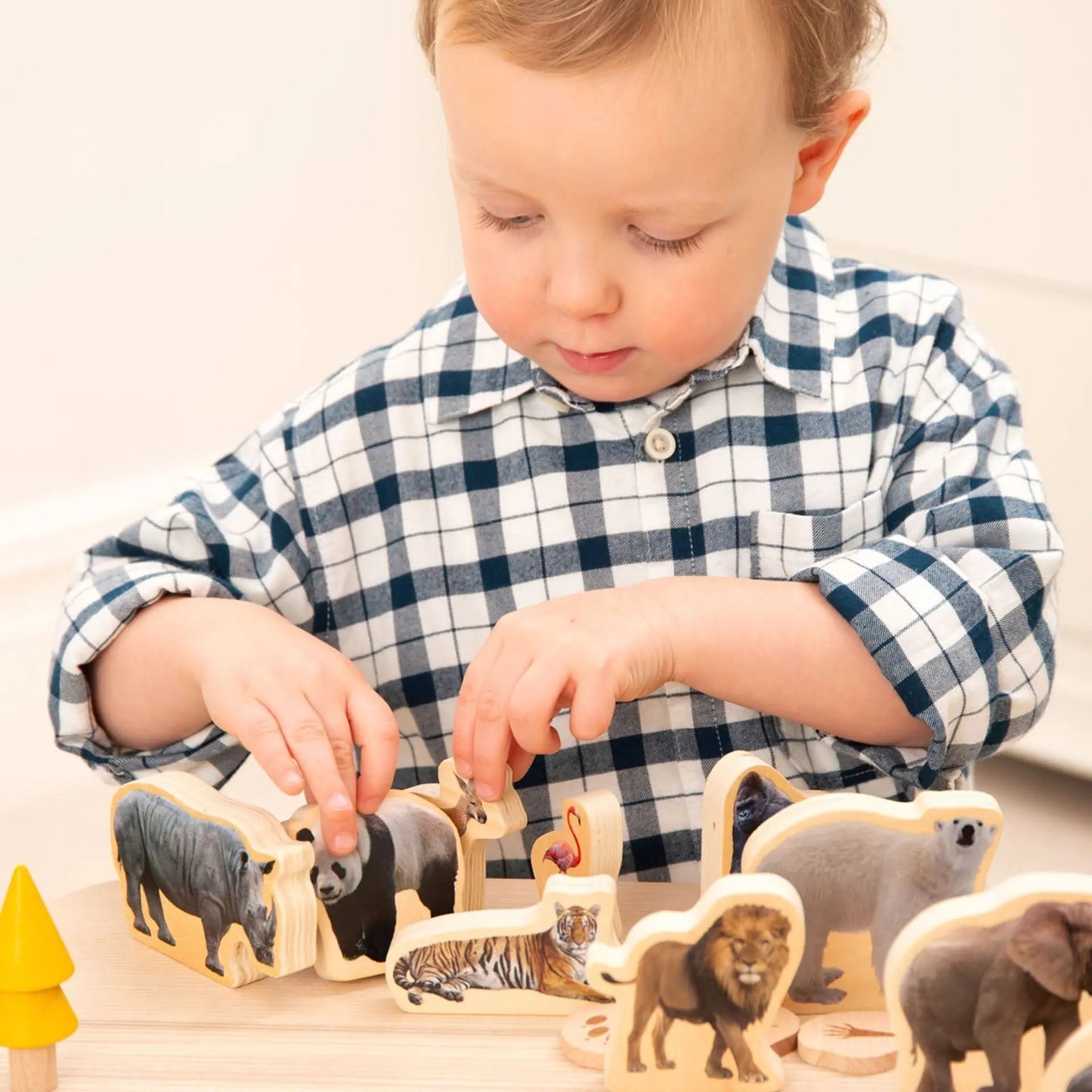 Child playing with wooden animal figurines on a light surface