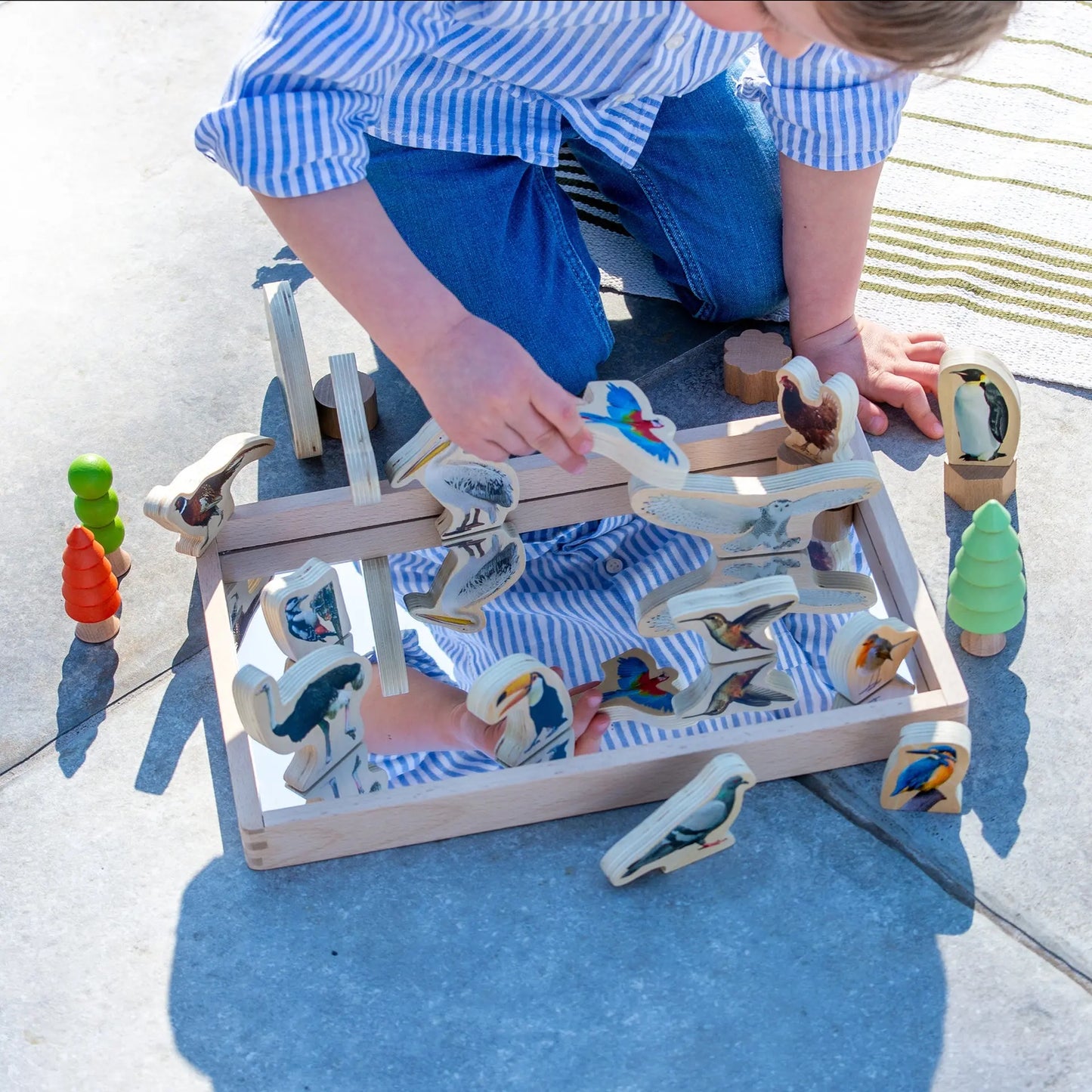 Child playing with a wooden toy set on a concrete surface