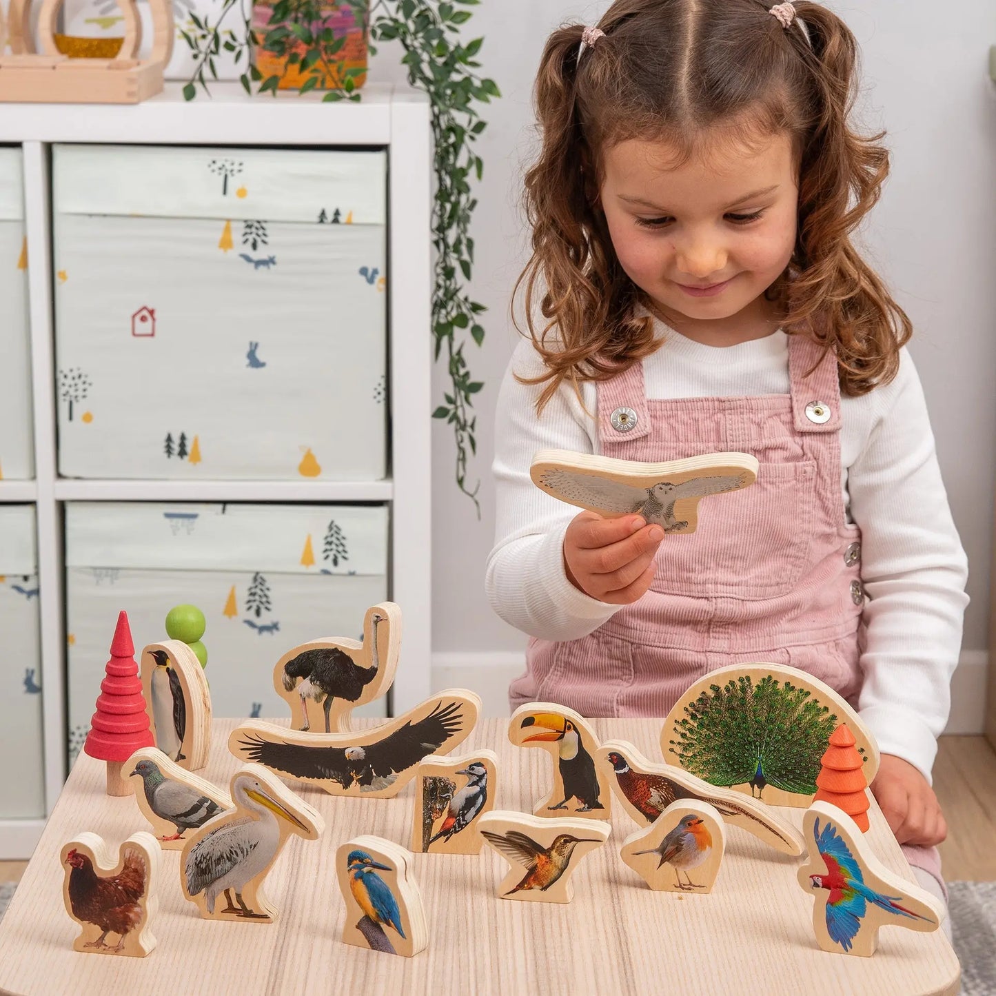 Child playing with wooden animal figurines in a room with a white dresser.