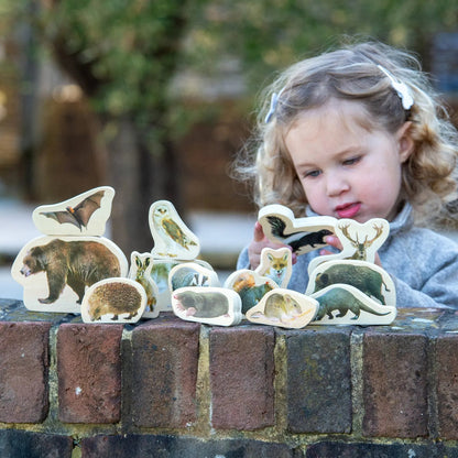 Child playing with animal figurines on a brick ledge outdoors
