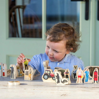 Child playing with wooden figurines on a table outdoors