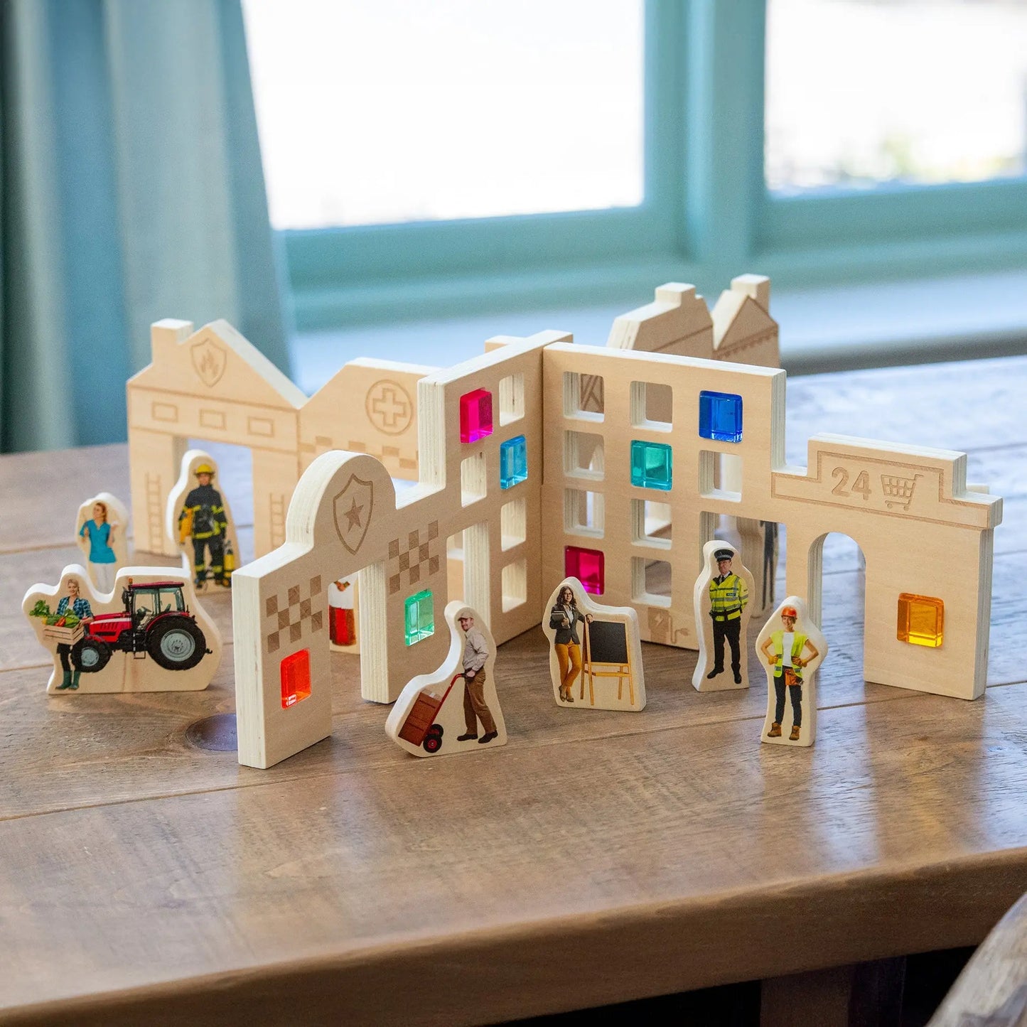 Wooden toy town set with colourful windows and small figures on a wooden surface.