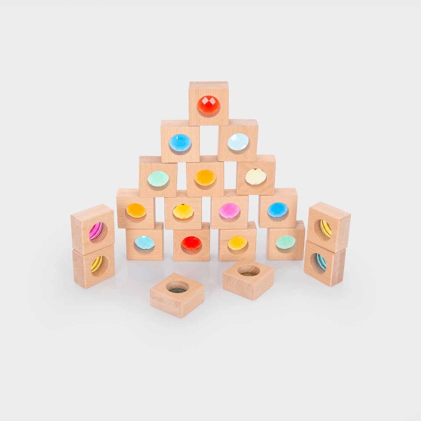 Wooden blocks with colourful shapes arranged in a pyramid on a light grey background