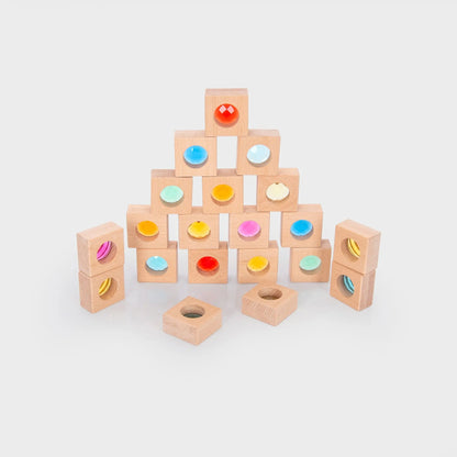 Wooden blocks with colourful shapes arranged in a pyramid on a light grey background