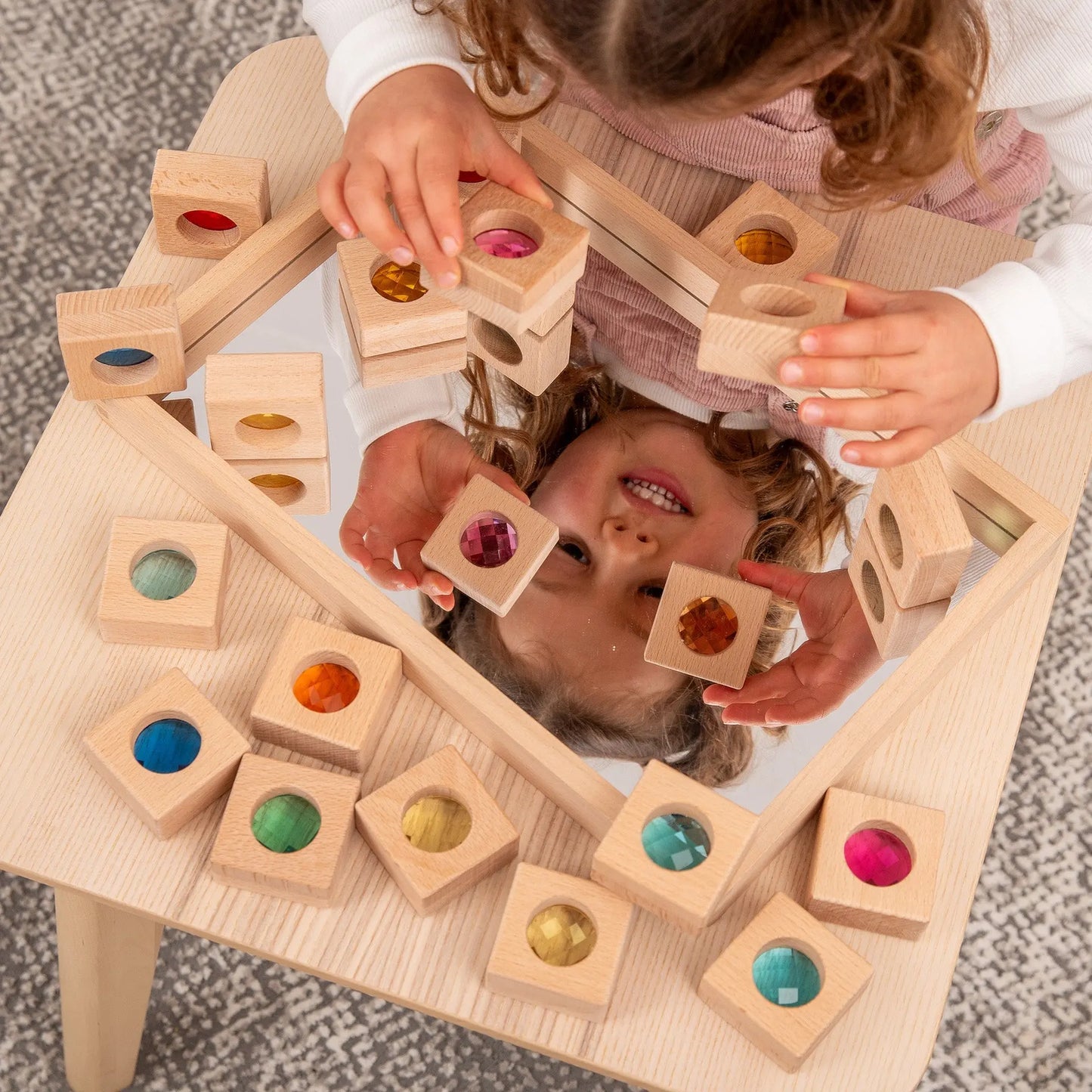 Child playing with wooden blocks on a mirror