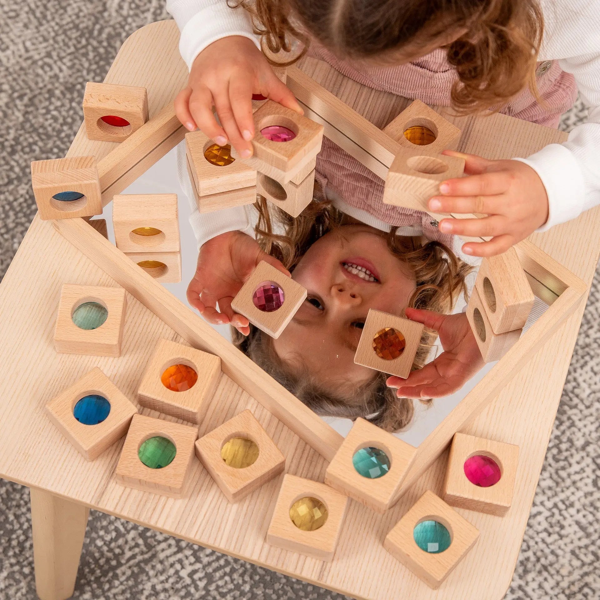 Child playing with wooden blocks on a mirror