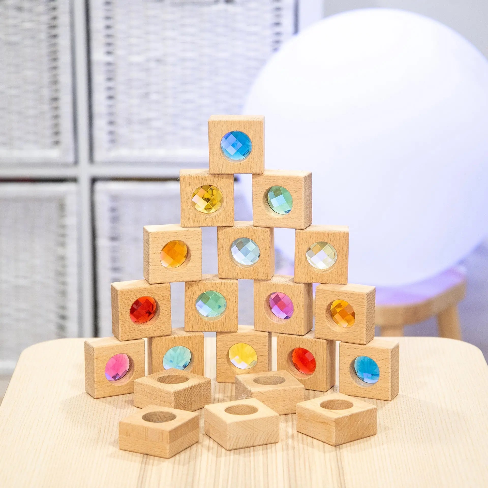 Stack of wooden blocks with coloured gemstones on a light surface