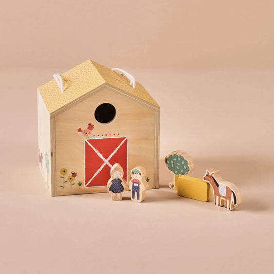 Wooden toy set with a barn-shaped box, figures, and animals on a beige background