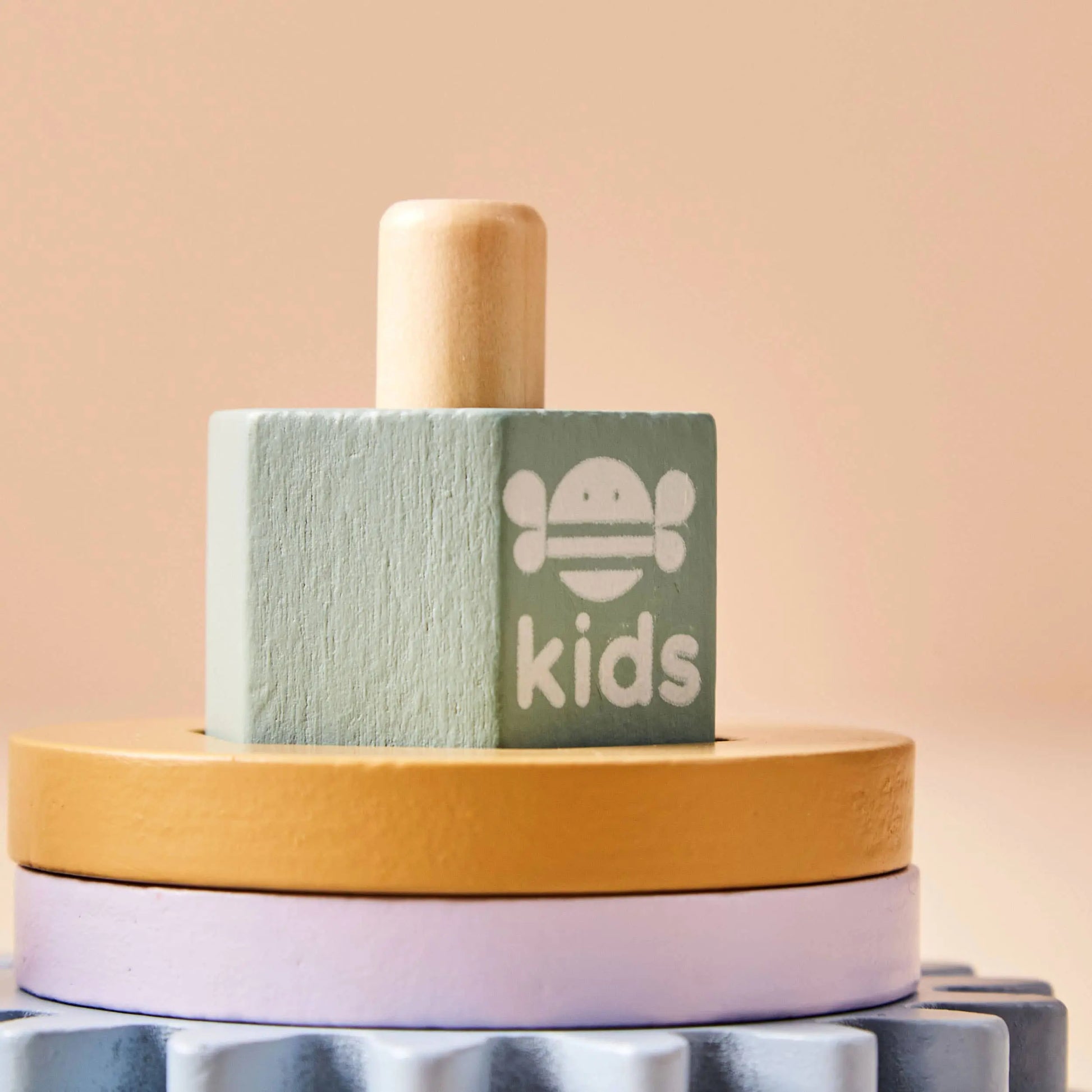 Colourful wooden blocks with 'kids' branding on a soft pink background