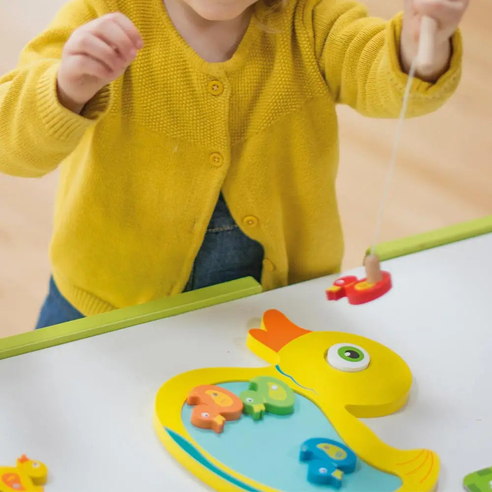 Child playing with a magnetic fishing game on a table