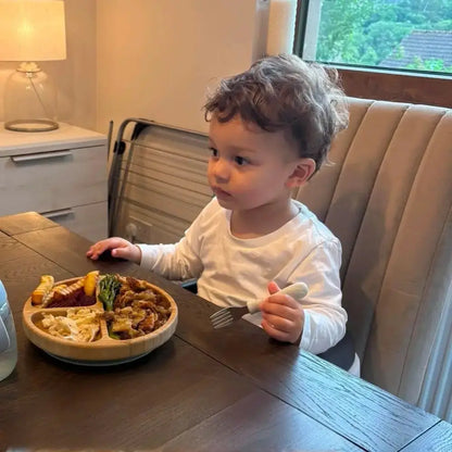 Toddler eating from a round bamboo divided suction plate