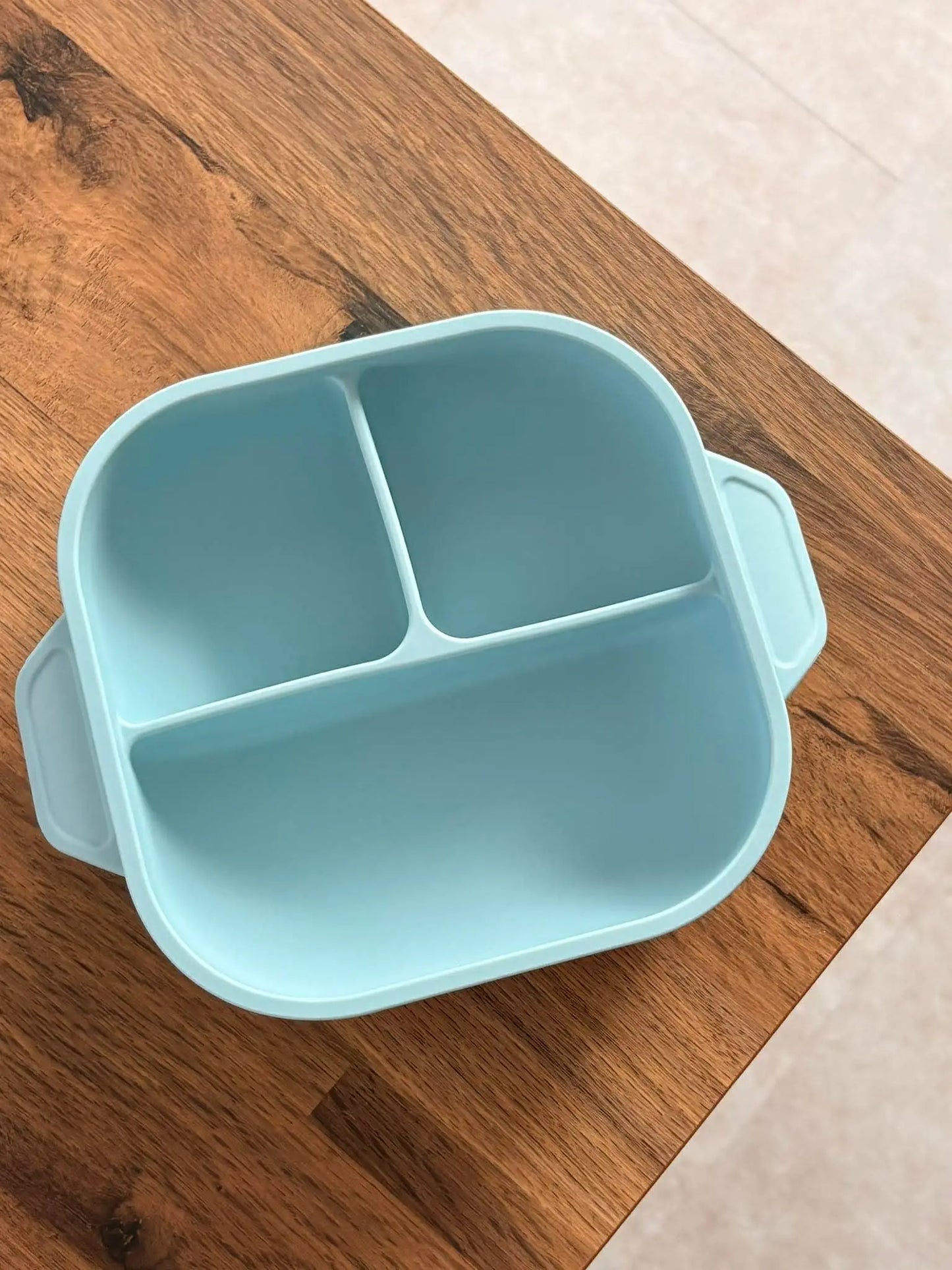 Light blue divided bowl on a wooden surface