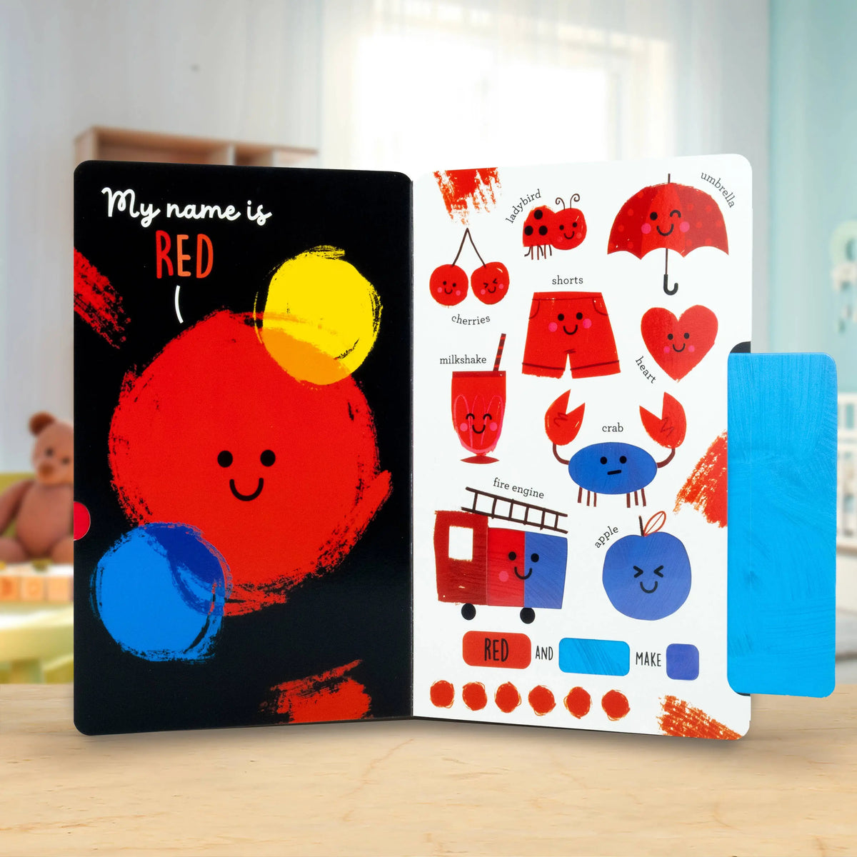Colourful children's book with a red character and sticker sheet on a wooden surface.