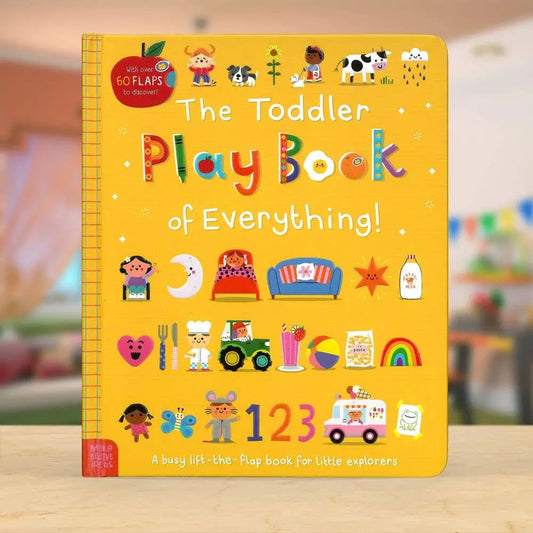 The Toddler Play Book of Everything! by Wrigley's, a bright yellow board book with colourful cartoon illustrations and playful title lettering, standing on a light wooden surface with a softly blurred indoor background.