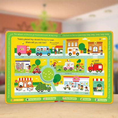 Children's educational board book with colourful illustrations of a bus route and vehicles on a wooden surface.