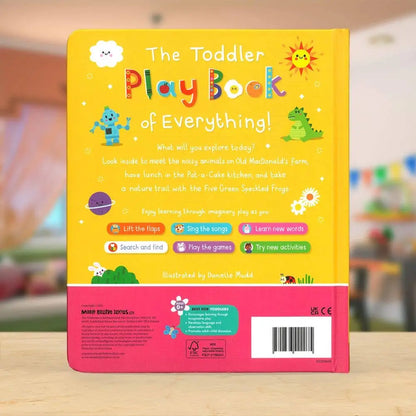 The back cover of a children's book titled 'The Toddler Play Book of Everything!' shown standing upright on a light wooden surface. The cover is predominantly bright yellow on the upper portion and pink on the lower portion, with colourful playful illustrations including a smiling sun, clouds, animals, and activity icons.