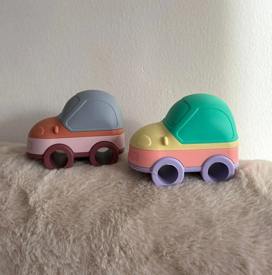 Two colourful toy cars on a textured surface with a plain background
