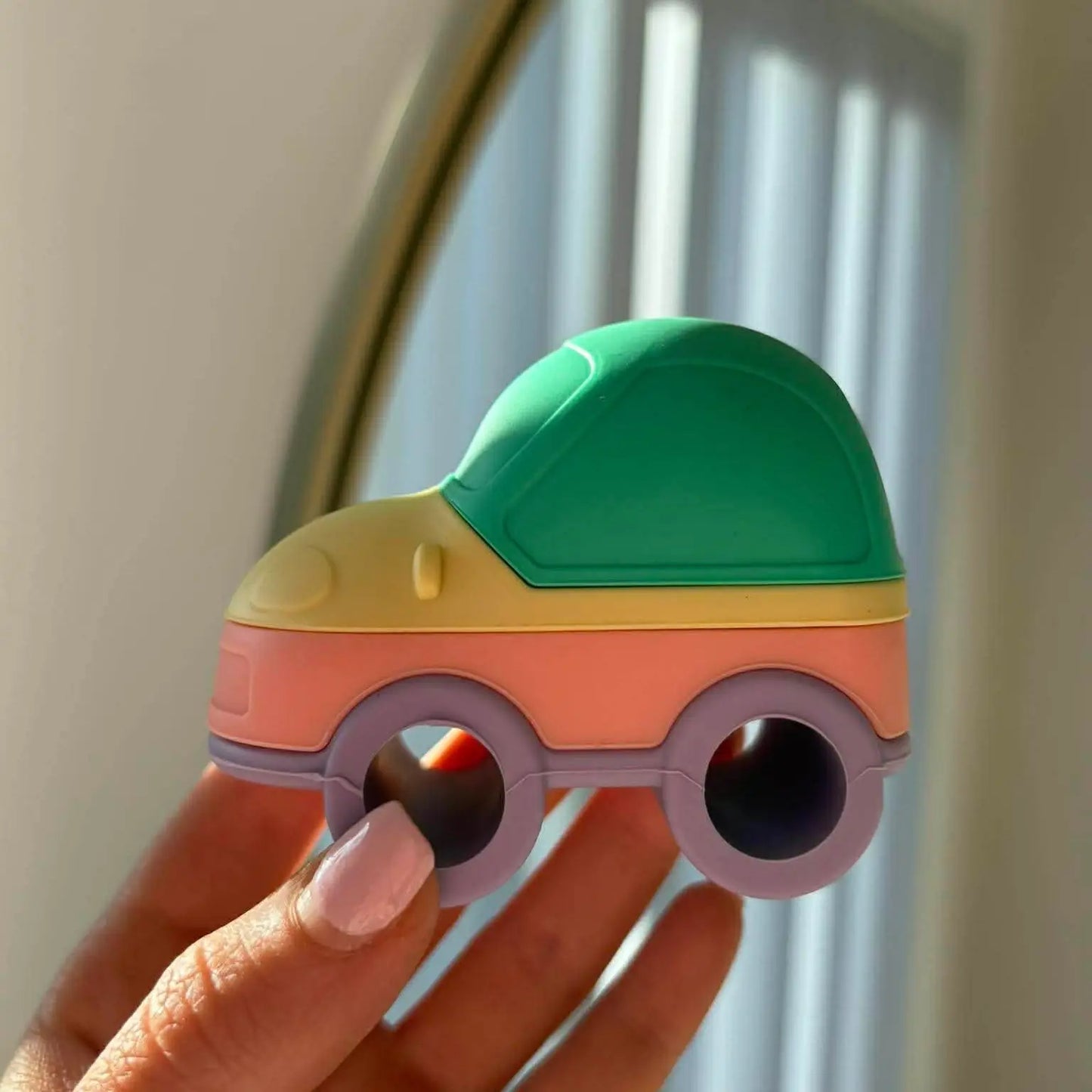 Colourful car-shaped object held in front of a mirror