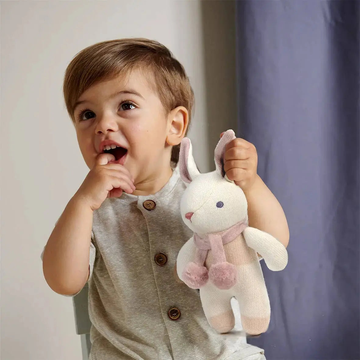 Child holding a plush toy with a plain background