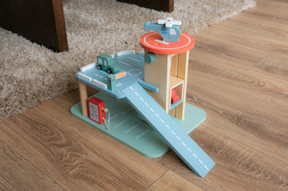 Toy set with a helicopter, cars, and a ramp on a wooden floor.