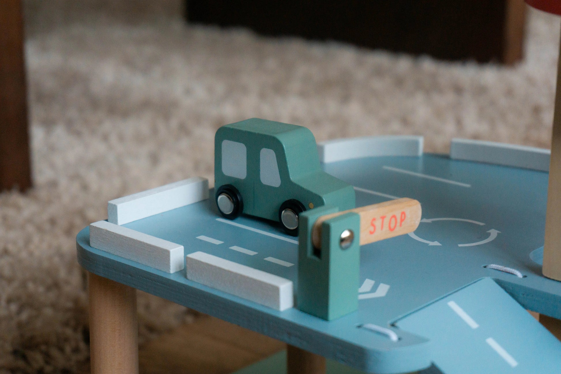 Wooden toy car on a blue play road with a stop sign