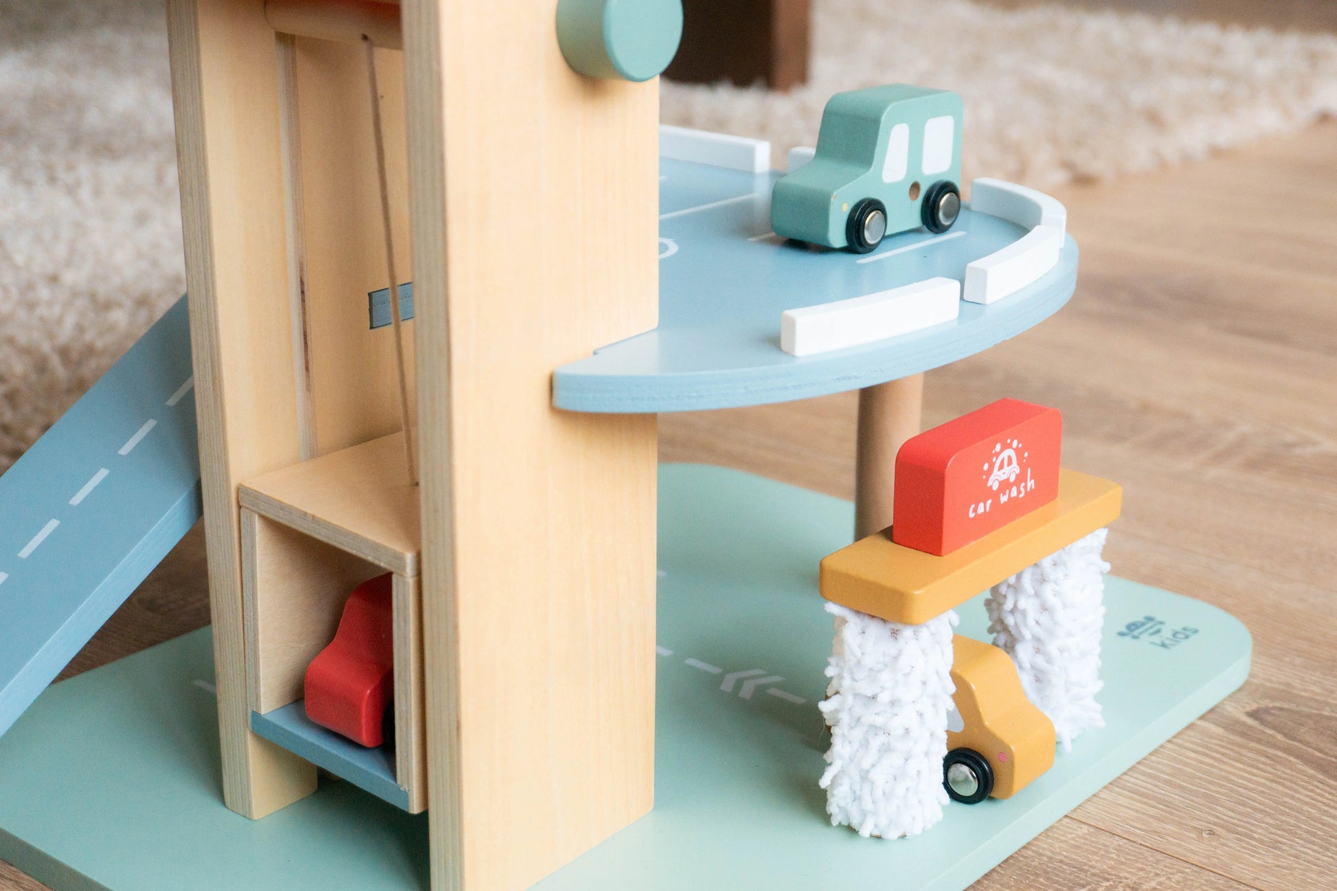 Wooden toy car ramp with cars on a wooden floor