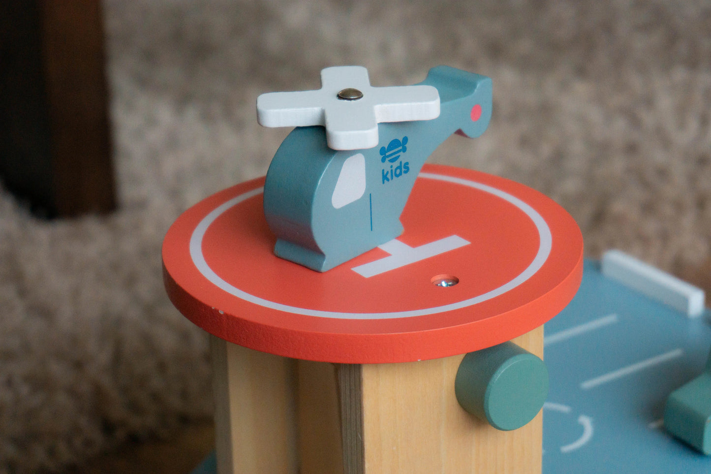 Toy helicopter on a red platform with 'Just Bee Kids' branding, blurred background