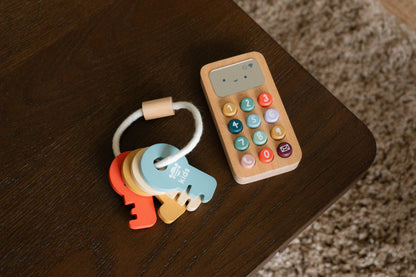 Colourful toy keys and wooden phone on a dark surface