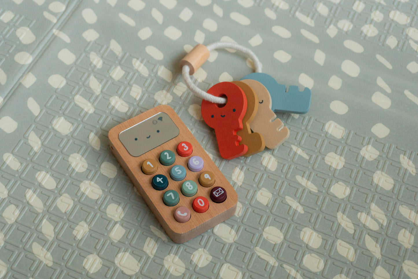 Wooden toy phone with colourful buttons on a patterned surface