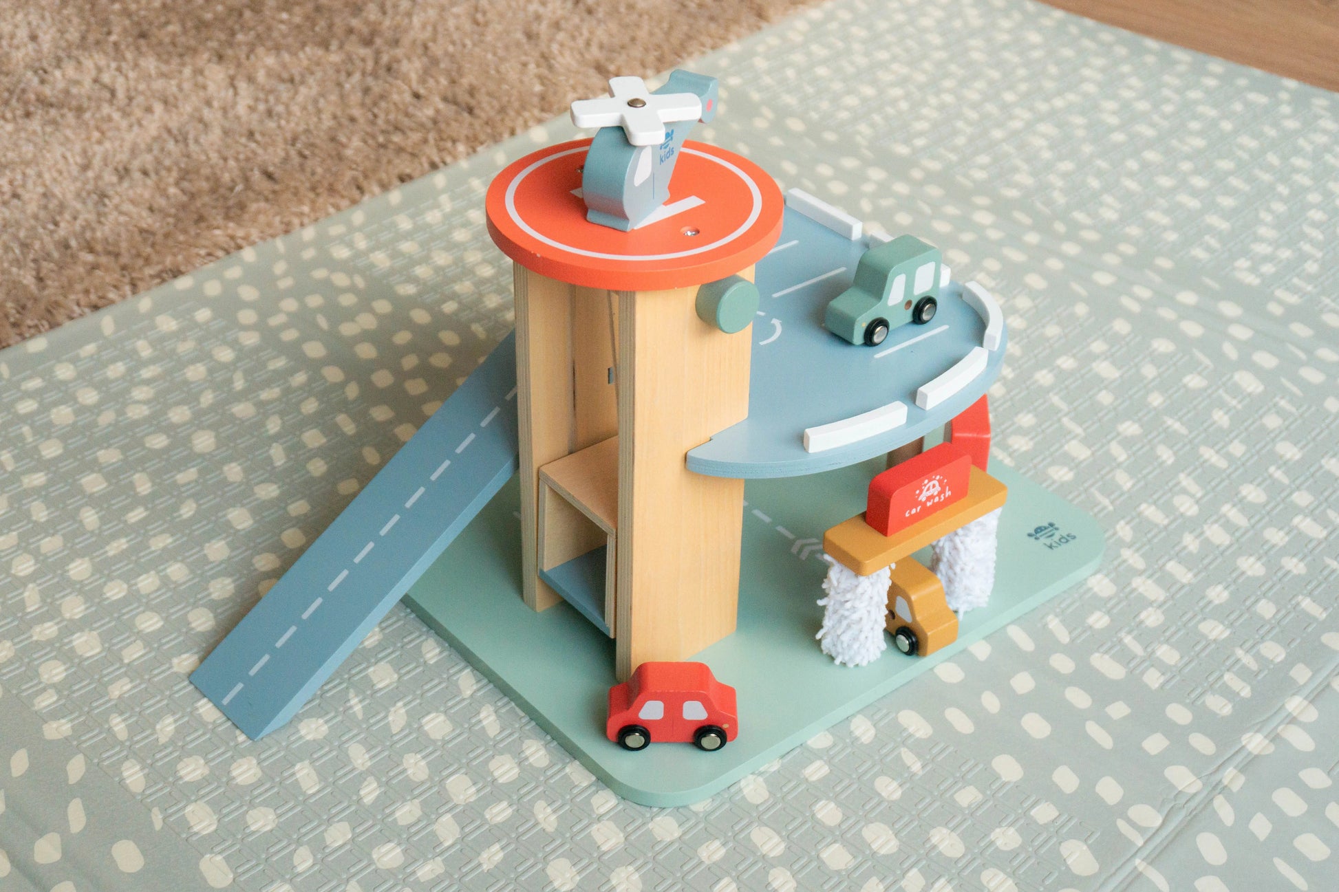 Toy wooden car garage on a patterned surface.