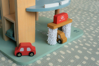 Wooden toy car wash set with red car and yellow car on a patterned surface