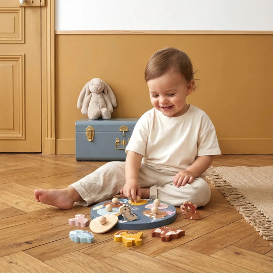Child playing with toys on a wooden floor with a suitcase and plush toy in the background.