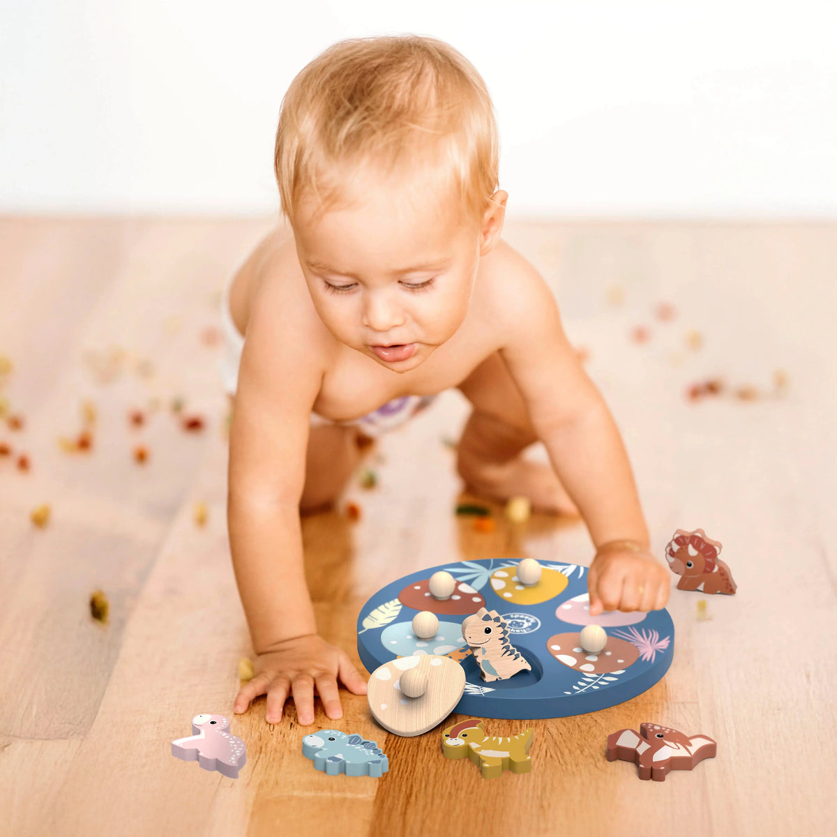 Baby playing with a wooden toy on a wooden floor.
