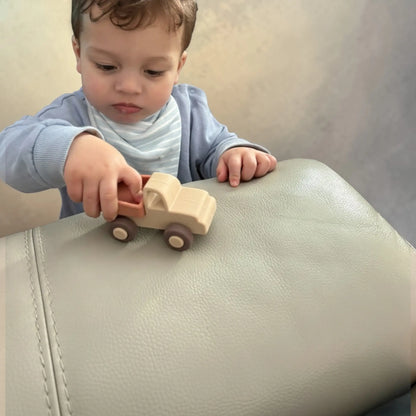 Child playing with a silicone toy car on a light-coloured surface