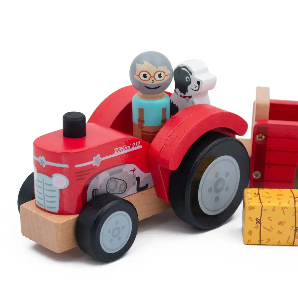 Wooden toy tractor with figurines and a dog on a white background
