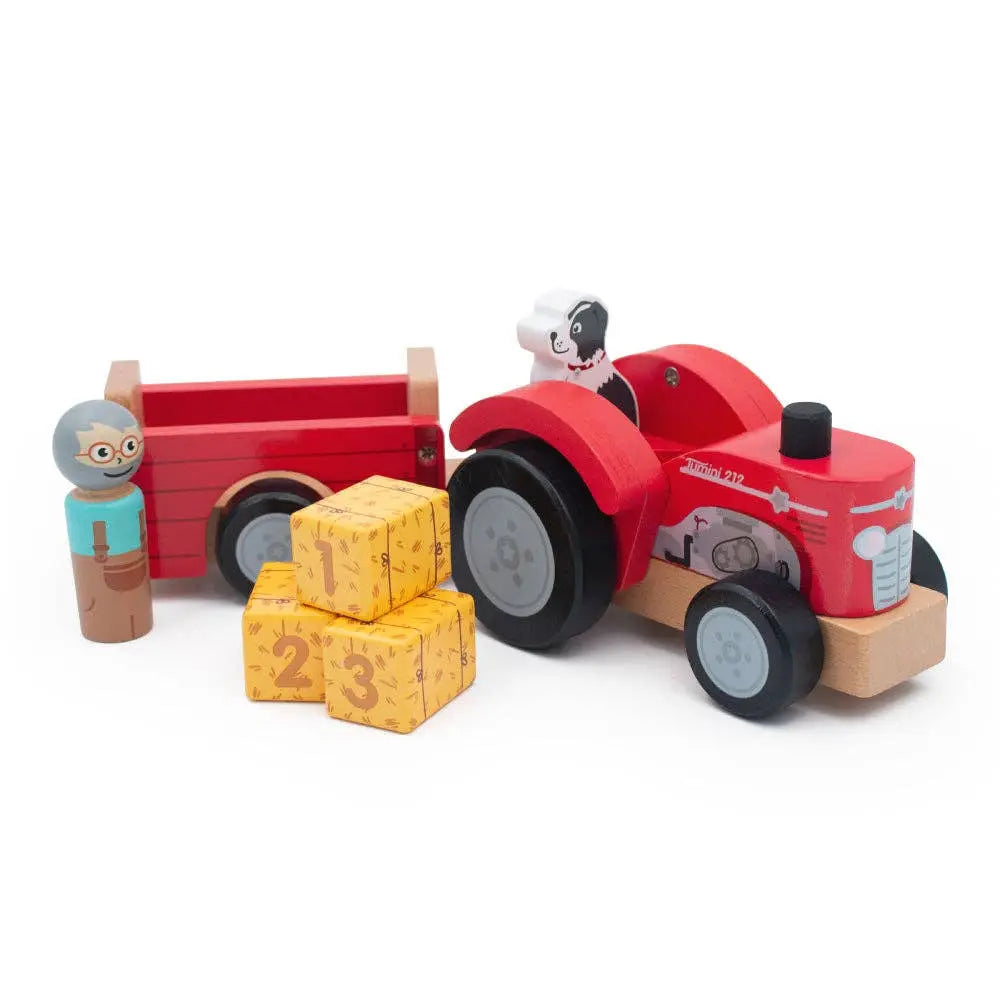 Wooden toy tractor with a red trailer, blocks, and figures on a white background