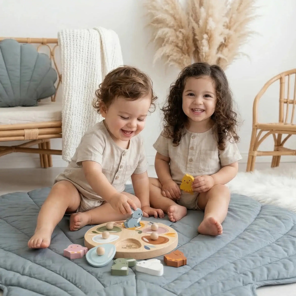 Two children playing with wooden toys on a quilted blanket in a cozy room.