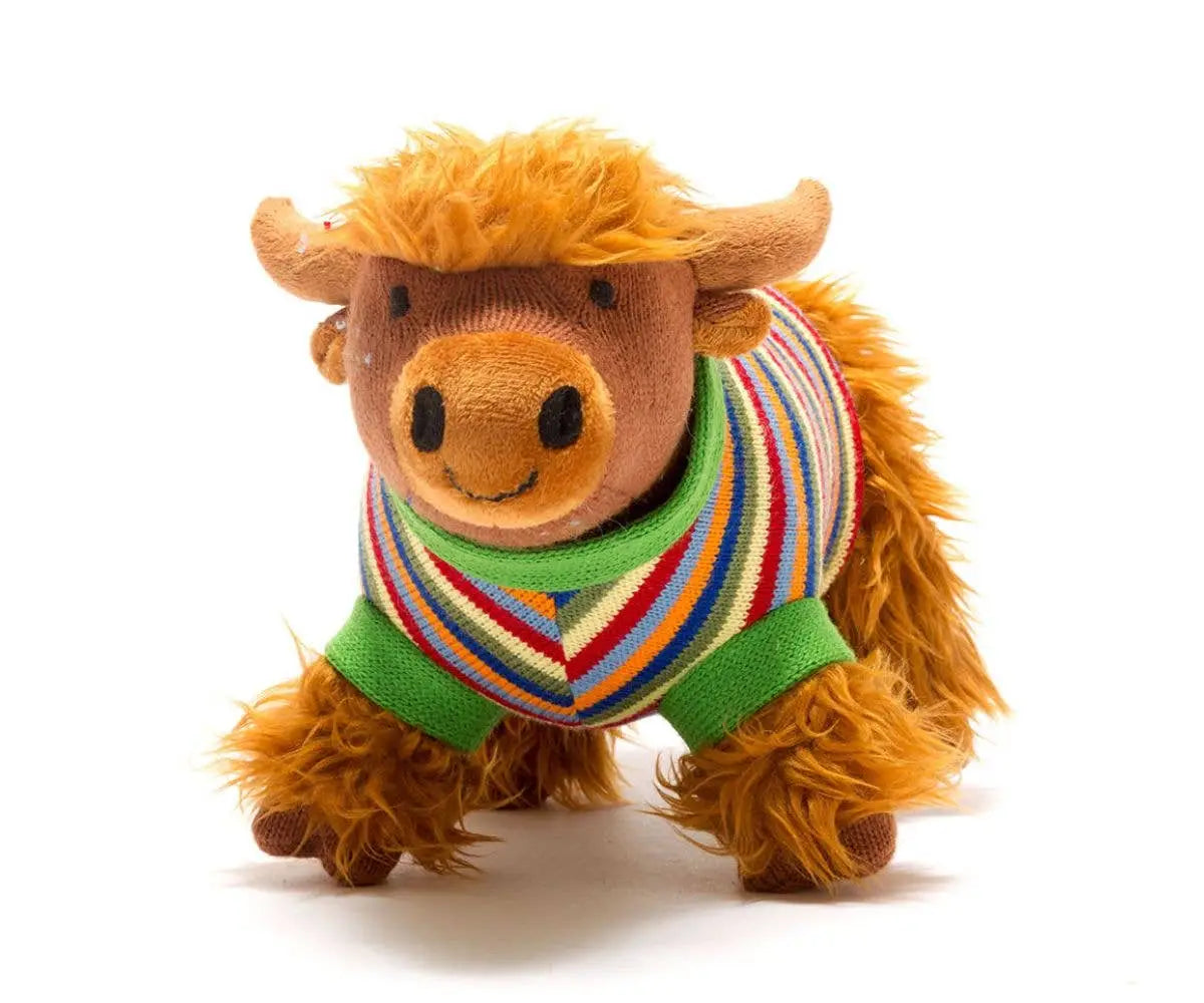 Plush toy cow wearing a colourful sweater on a white background