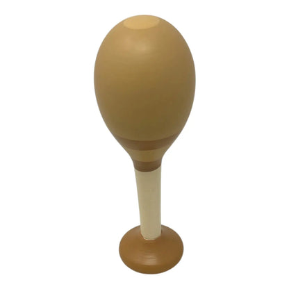 A wooden maraca with a rounded, egg-shaped head in a warm brown tone, a cream-colored shaft, and a circular base, shown against a plain white background.