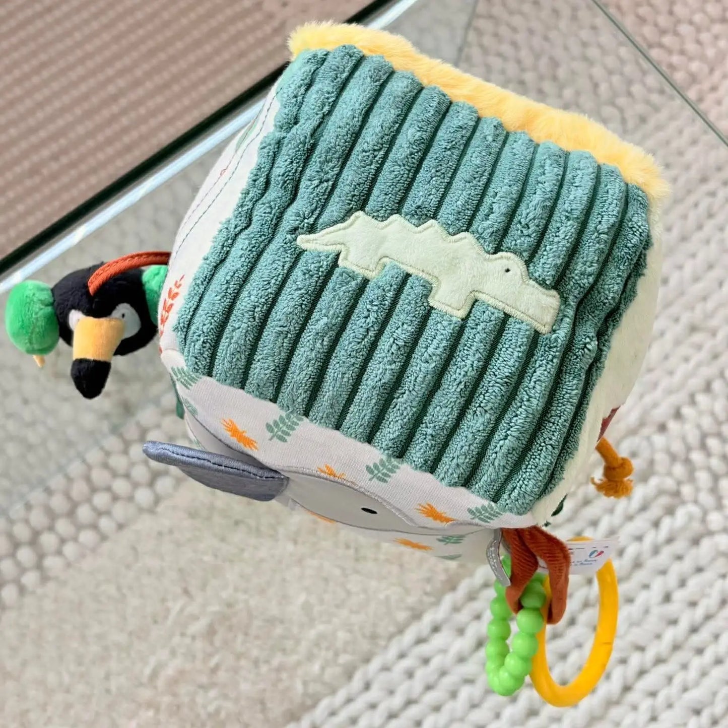 Textured green toy with a cartoon character on a glass surface