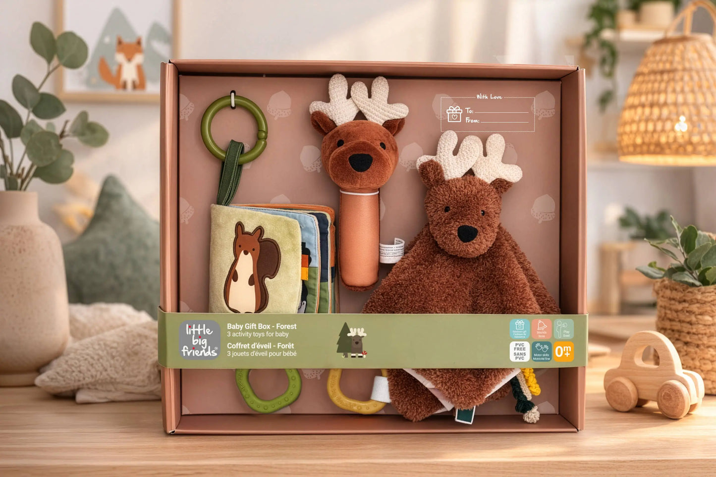 Baby gift set with toys and a book in a box on a wooden surface.