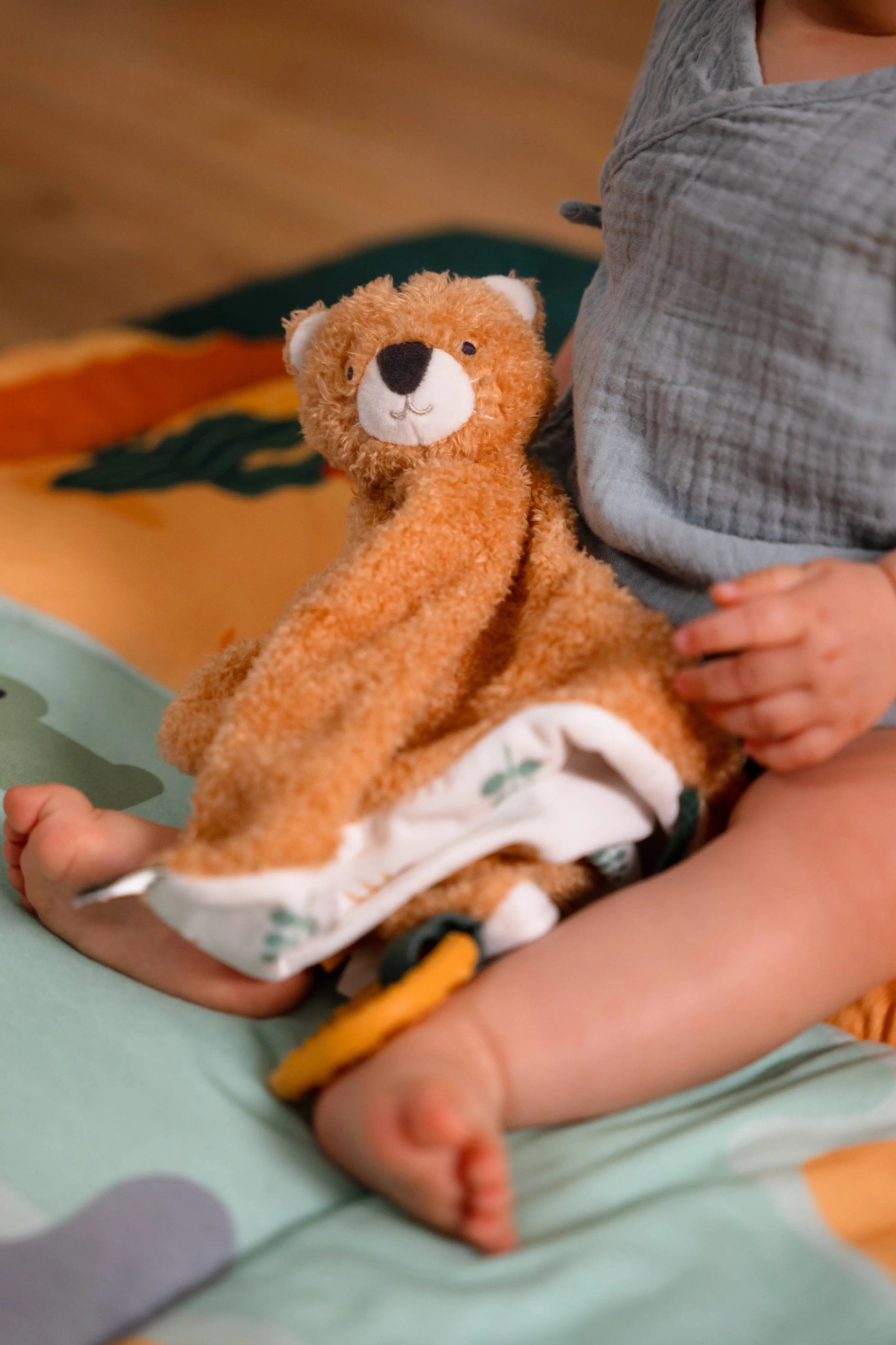 Child playing with a plush tiger in a nappy on a green blanket