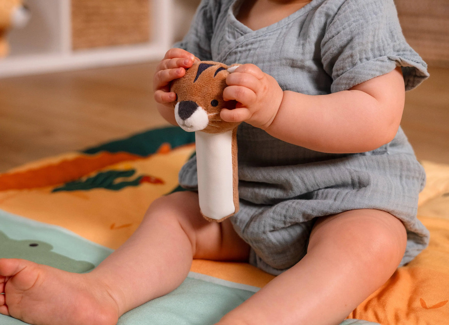 Baby holding a plush toy on a colourful play mat